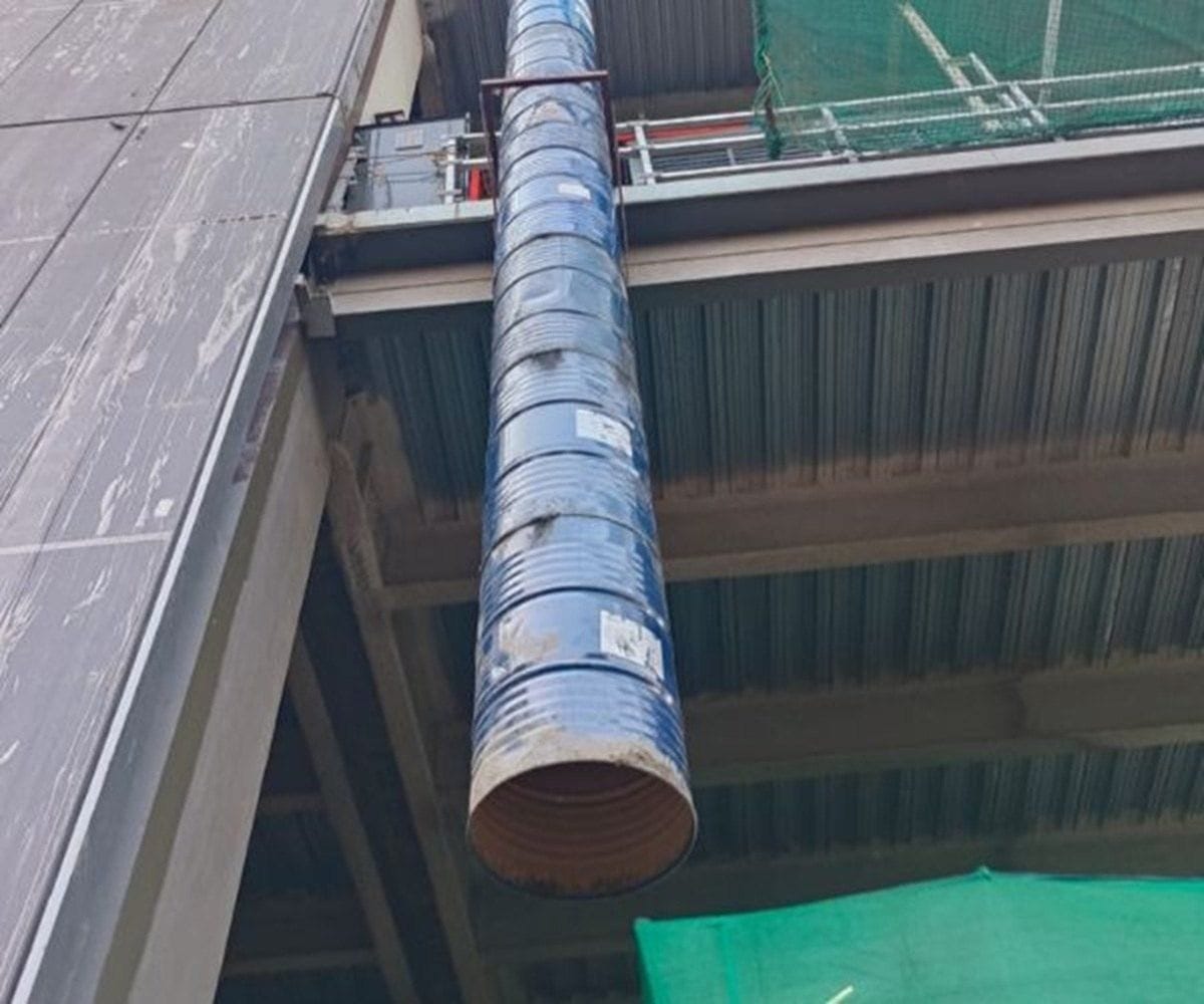 Debris chute outlet fixed below a slab edge for controlled debris removal at a Pune site